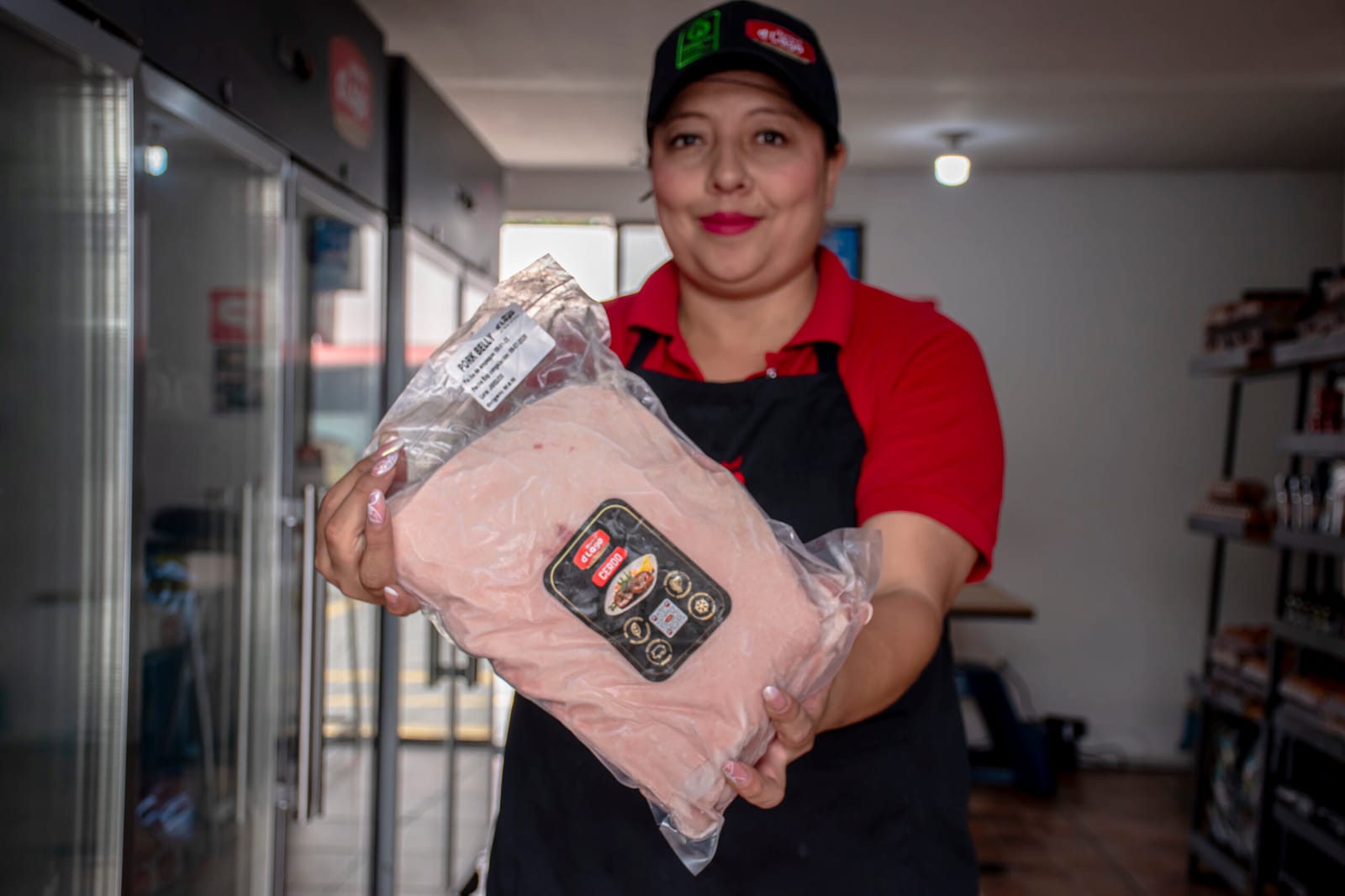 A shop adviser holds a vacuum packed cut in front of the counter