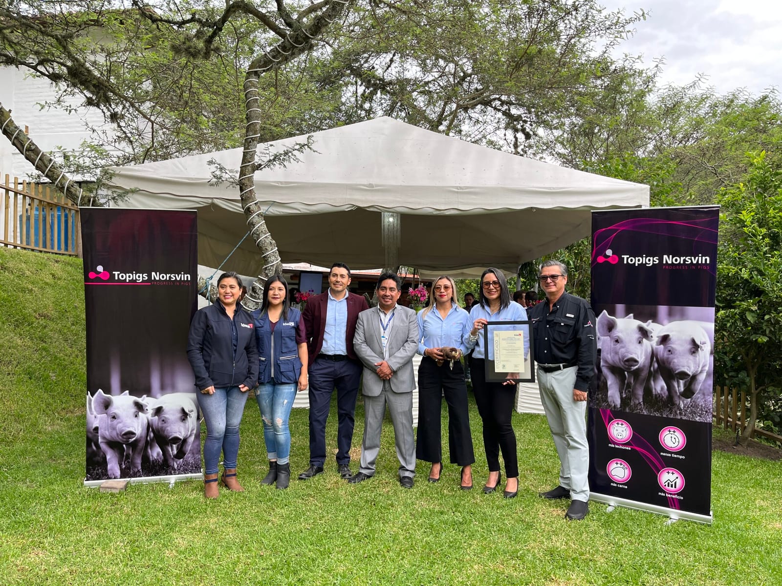 Entrega del certificado Welfair al equipo de Topigs Norsvin Ecuador, junto a los carteles de la marca