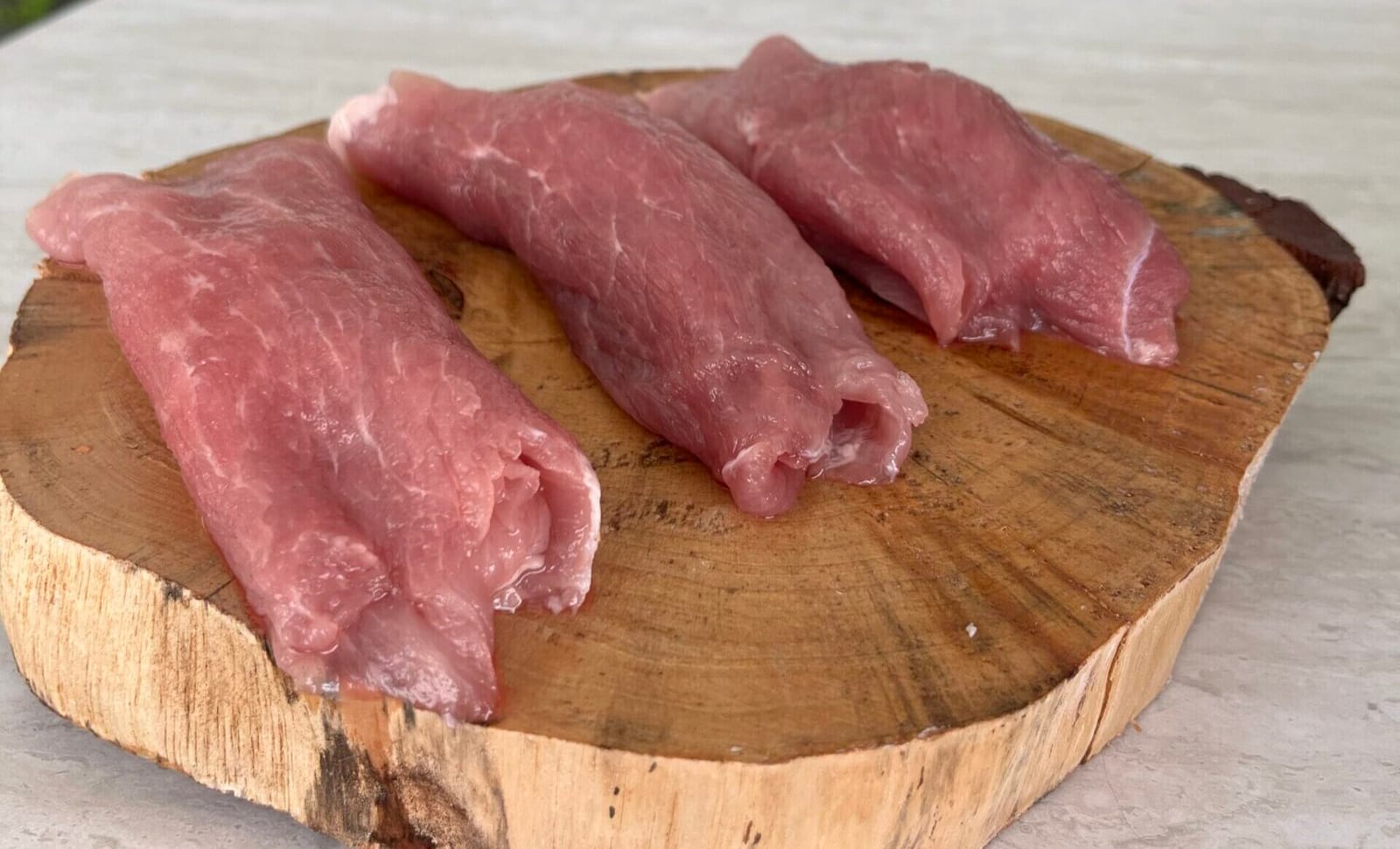 Three pork loins on a wooden board