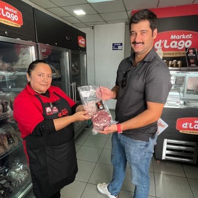 An adviser hands a packaged product to a customer inside a Market d'Lago shop