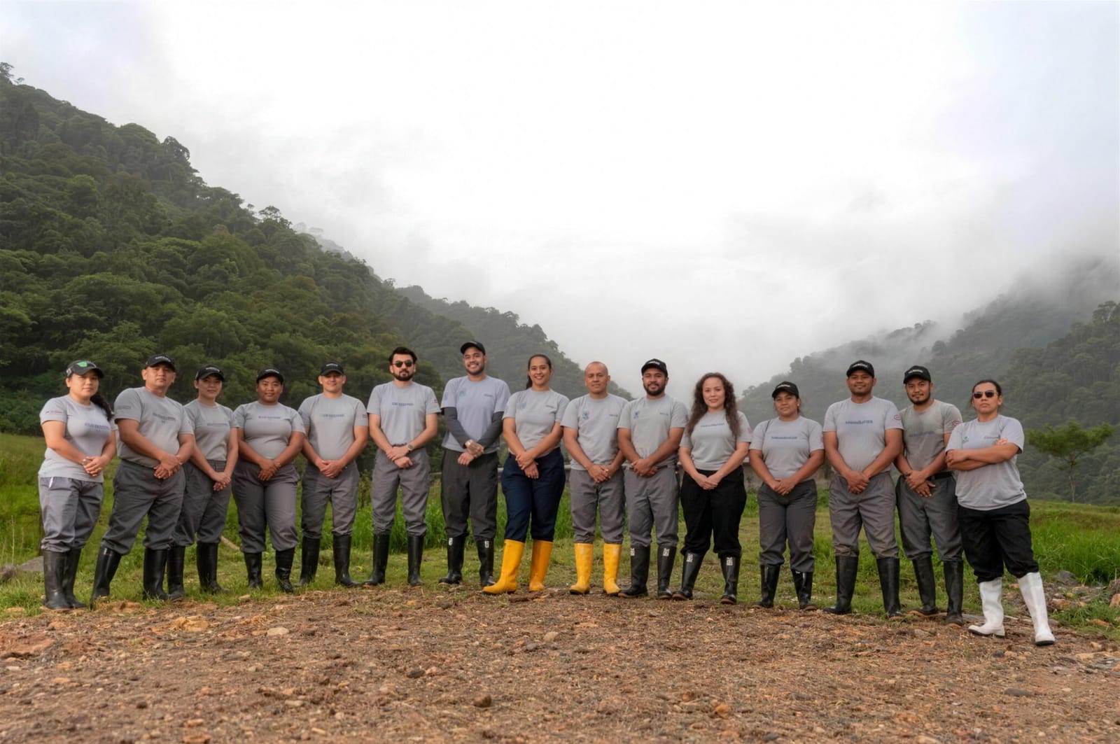 A equipe da Agroindustrias González, alinhada em uma clareira com a floresta e a névoa da montanha ao fundo