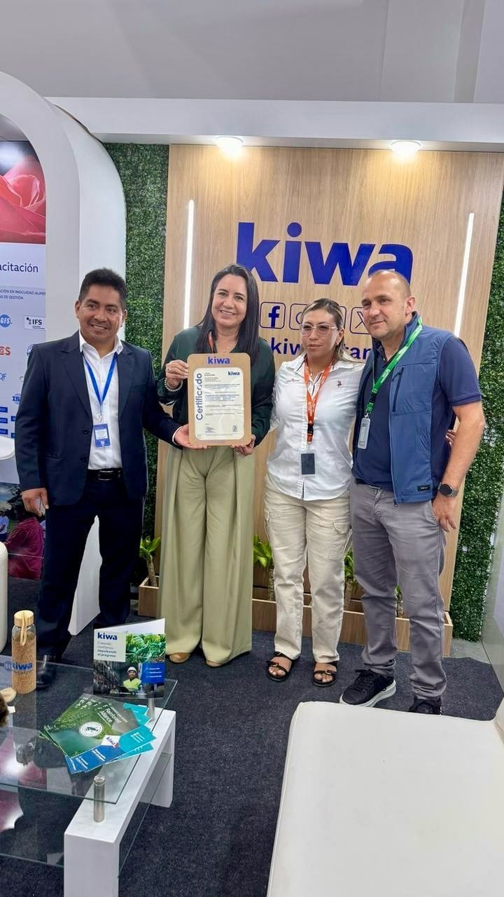Cuatro personas posan en el stand de la certificadora Kiwa; una de ellas sostiene un certificado enmarcado